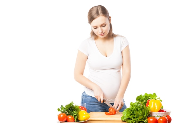 Ritratto di donna incinta che prepara insalata. Studio shot