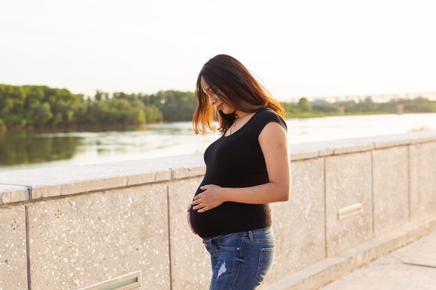 Ritratto di donna incinta ispanica che cammina in un parco al tramonto concetto di gravidanza e maternità