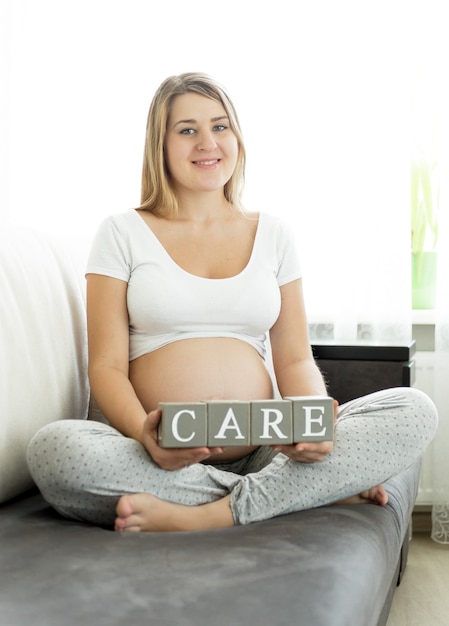 Ritratto di donna incinta tenendo le lettere che fanno la parola Care