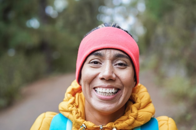 Ritratto di donna latina che si diverte durante la giornata di trekking nel bosco - Focus on face