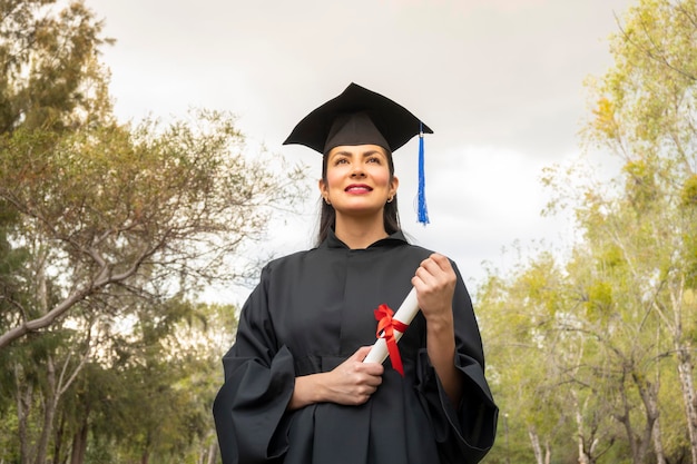 Ritratto di donna latina con abito scolastico che tiene il suo concetto di laurea di laurea