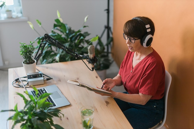 Ritratto di donna matura che indossa le cuffie e parla al podcast e alla broadca della stazione radio online