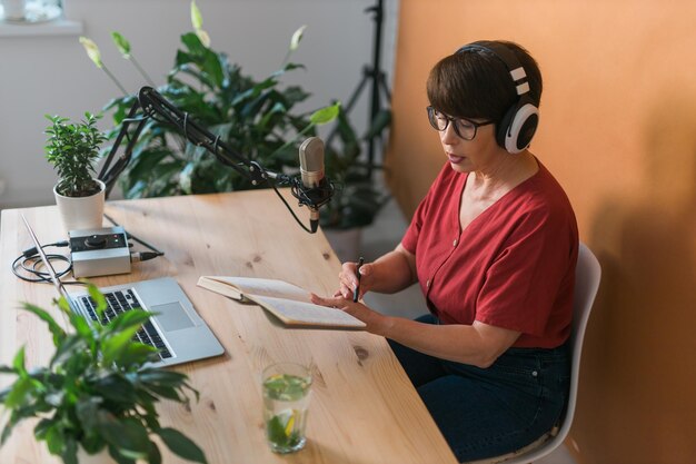 Ritratto di donna matura che indossa le cuffie e parla al podcast e alla broadca della stazione radio online