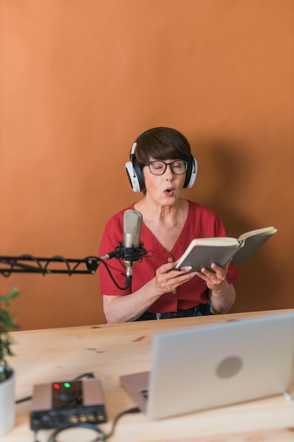 Ritratto di donna matura che indossa le cuffie e parla al podcast e alle trasmissioni della stazione radio online