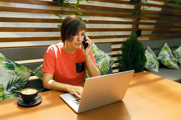 ritratto di donna matura e sicura di sé che si siede sulla terrazza estiva al bar utilizzando laptop