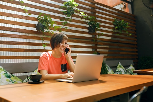 ritratto di donna matura e sicura di sé che si siede sulla terrazza estiva al bar utilizzando laptop