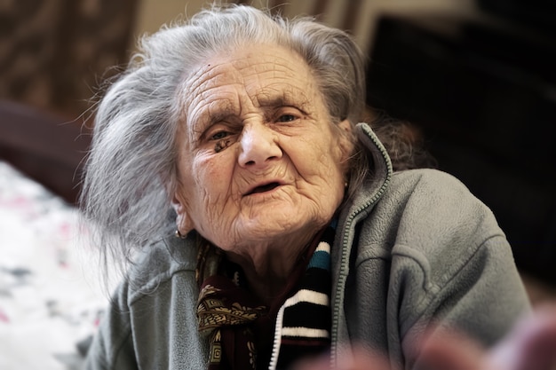 Ritratto di donna molto anziana stanca in depressione seduto al chiuso sul letto