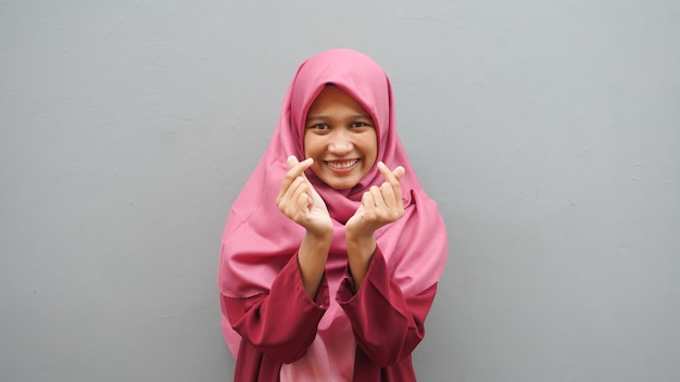 Ritratto di donna musulmana asiatica che sorride alla macchina fotografica e fa l'amore o fa un gesto con il segno del cuore con la mano