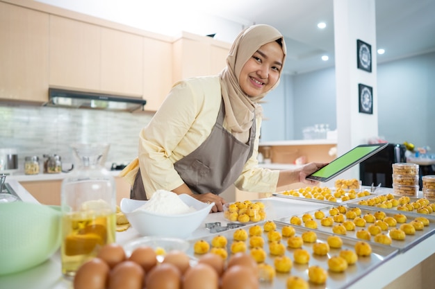 Ritratto di donna musulmana felice con snack nastar in cucina