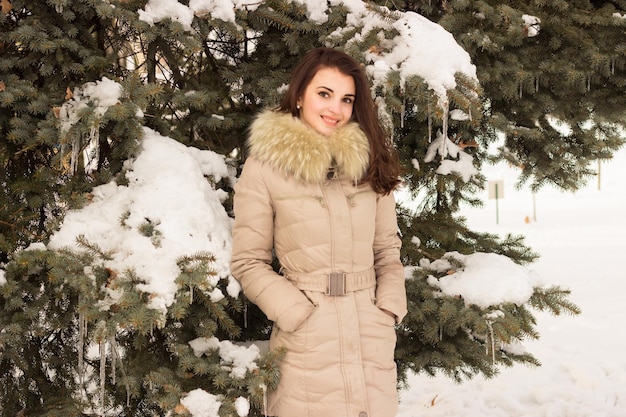 Ritratto di donna nel parco d'inverno vicino all'albero d'inverno