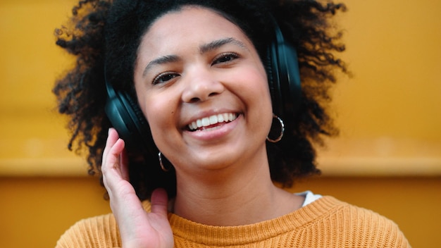 Ritratto di donna nera o cuffie musicali su sfondo giallo isolato moda mockup o parete mock up Sorridi studente felice o ridente ascoltando l'audio della radio e il podcast in un panno alla moda o alla moda