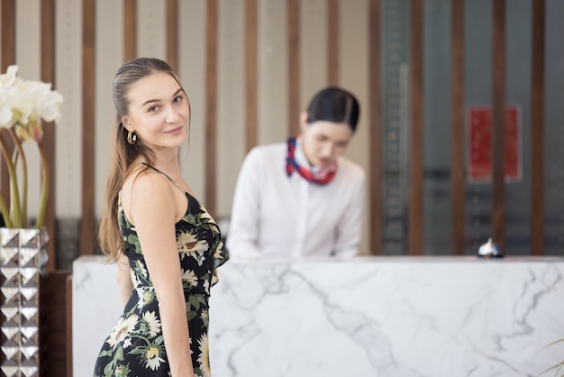 Ritratto di donna ospite con bagaglio in attesa di effettuare il check-in in hotel, concetto di lifestyle di viaggio felice