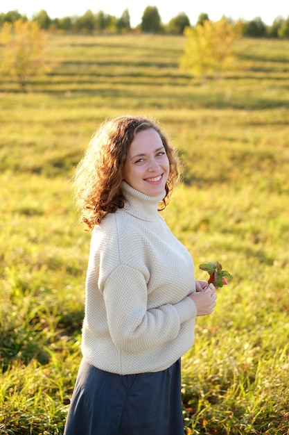 Ritratto di donna riccia dai capelli scuri sorridente mentre si trova in piedi nel paesaggio del campo