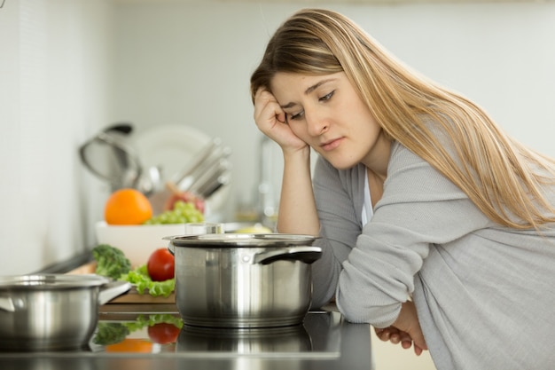 Ritratto di donna sconvolta che cucina zuppa in cucina