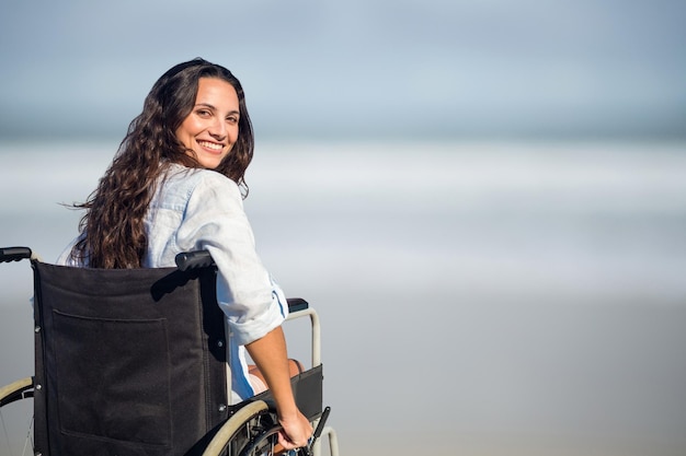 Ritratto di donna seduta su sedia a rotelle in spiaggia