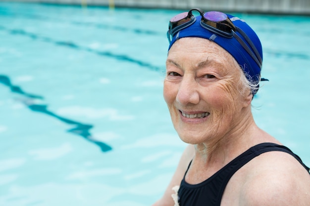 Ritratto di donna senior sorridente seduto a bordo piscina