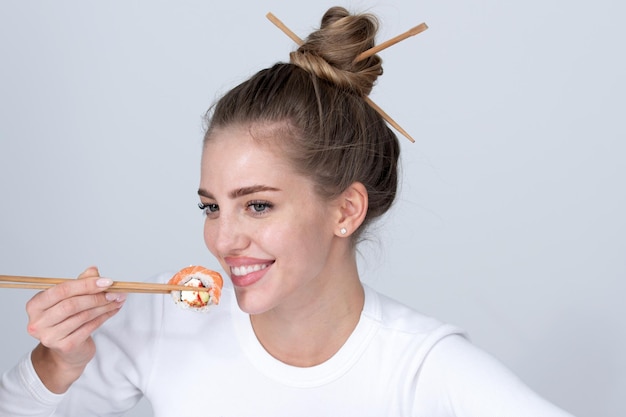 Ritratto di donna sexy di bellezza che mangia sushi Rotoli di sushi sashimi Ragazza del modello di moda che mangia Sushi con le bacchette Taglio di capelli con le bacchette che mangiano cibo giapponese sano