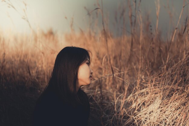 Ritratto di donna sola da sola in un campo Stile filtro vintageha il cuore spezzato dal concetto di ragazza amorosa sullo stile vintage tramonto