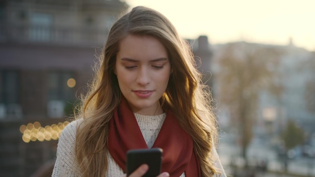 Ritratto di donna sorpresa che guarda lo schermo dello smartphone all'aperto Primo piano ragazza eccitata che legge il messaggio sul cellulare sulla strada della città Donna felice che grida sì con il cellulare in mano fuori