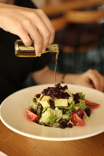 Ritratto di donna sorridente caucasica attraente che mangia insalata concentrarsi a portata di mano e forchetta