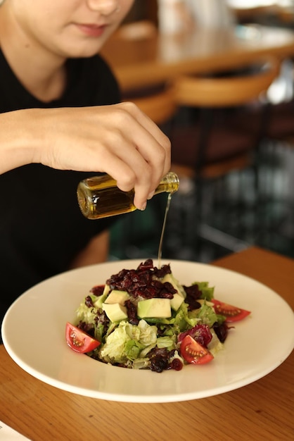 Ritratto di donna sorridente caucasica attraente che mangia insalata concentrarsi a portata di mano e forchetta