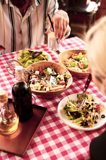 Ritratto di donna sorridente caucasica attraente che mangia insalata concentrarsi a portata di mano e forchetta