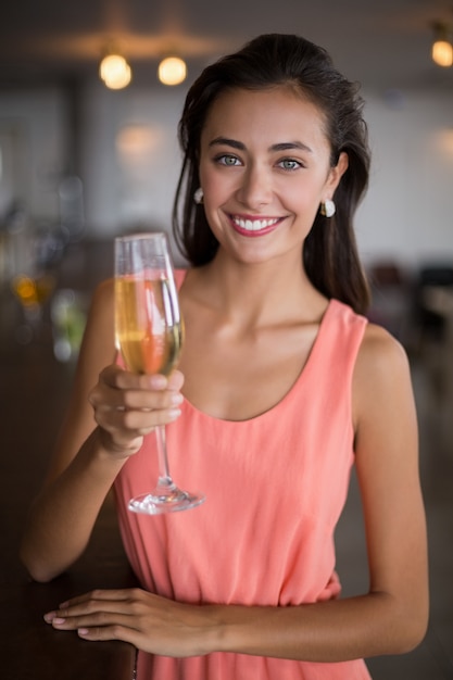 Ritratto di donna sorridente che tiene un bicchiere di champagne