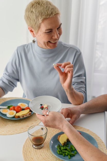 Ritratto di donna sorridente di mezza età in buona salute che prende la pillola della medicina prima di cena