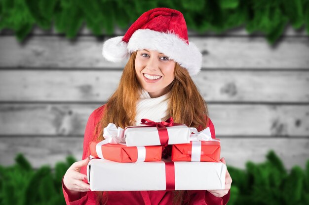 Ritratto di donna sorridente in costume da Babbo Natale che tiene i regali di Natale