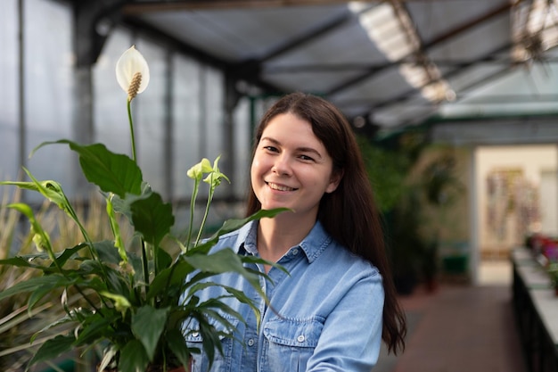 Ritratto di donna sorridente in serra con spathiphyllum nel vaso