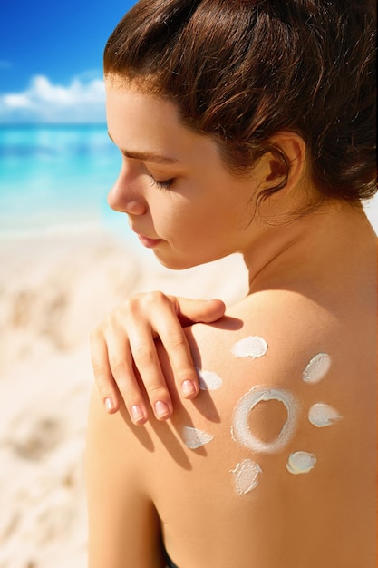 Ritratto di donna splendida in bikini con il sole disegnato su una spalla in spiaggia