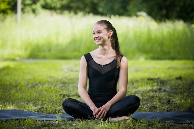 Ritratto di donna sportiva facendo esercizi di stretching nel parco prima dell'allenamento