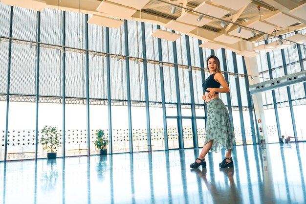 Ritratto di donna sulla terrazza di un belvedere della città in un edificio di vetro con una gonna verde