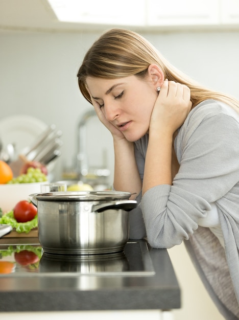 Ritratto di donna triste appoggiata al tavolo in cucina