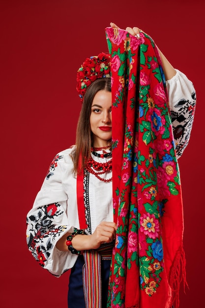 Ritratto di donna ucraina in abiti etnici tradizionali e ghirlanda floreale rossa con fazzoletto su sfondo studio viva magenta Abito ricamato nazionale ucraino chiamata vyshyvanka