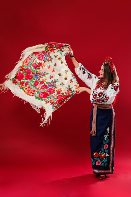Ritratto di donna ucraina in abiti etnici tradizionali e ghirlanda floreale rossa con fazzoletto su sfondo studio viva magenta Abito ricamato nazionale ucraino chiamata vyshyvanka