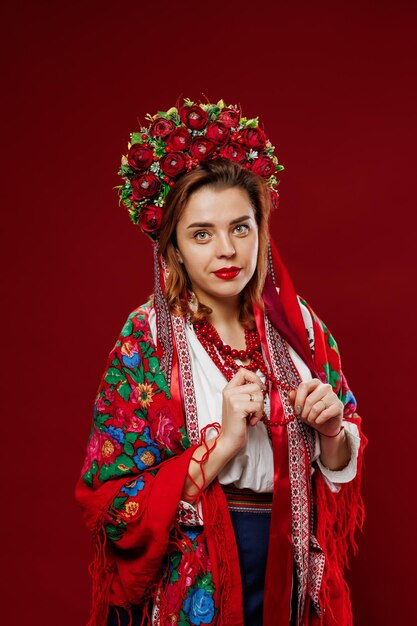 Ritratto di donna ucraina in abiti etnici tradizionali e ghirlanda floreale rossa su sfondo studio magenta viva Abito ricamato nazionale ucraino chiamata vyshyvanka Prega per l'Ucraina