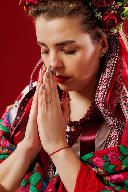 Ritratto di donna ucraina in abiti etnici tradizionali e ghirlanda floreale rossa su sfondo studio magenta viva Abito ricamato nazionale ucraino chiamata vyshyvanka Prega per l'Ucraina
