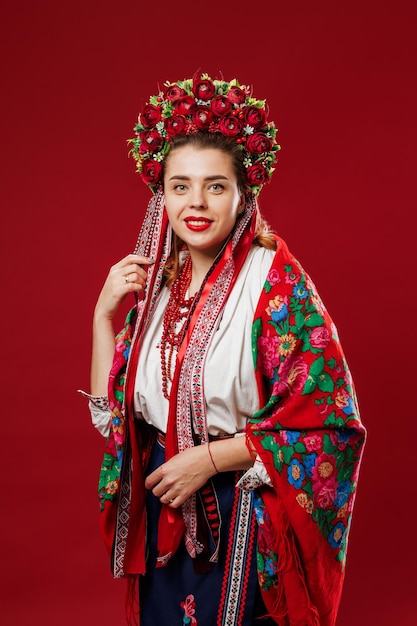 Ritratto di donna ucraina in abiti etnici tradizionali e ghirlanda floreale rossa su sfondo studio magenta viva Abito ricamato nazionale ucraino chiamata vyshyvanka Prega per l'Ucraina