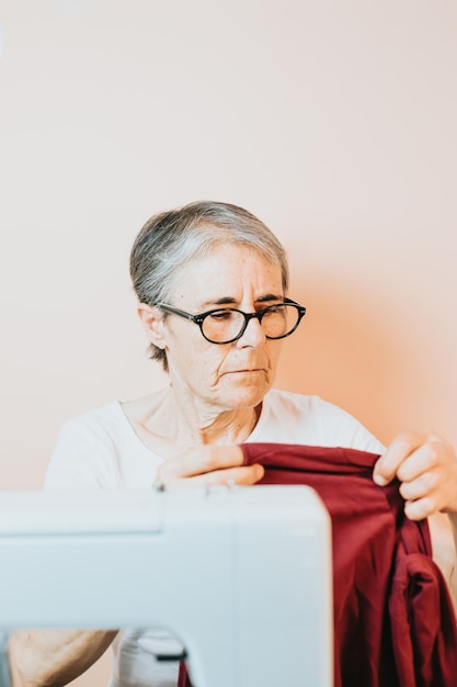 Ritratto di donna vestiti fogna nella preparazione dei tessuti per lavorare su una macchina sarta anziana che taglia un pezzo di stoffa mentre lavora in officina lavorando la vecchia tecnologia della macchina da cucire del passato