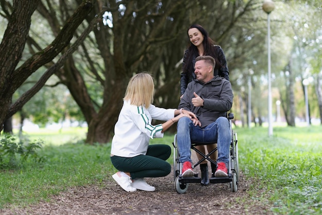 Ritratto di donne amiche che camminano con un uomo disabile in sedia a rotelle nella disabilità del parco e