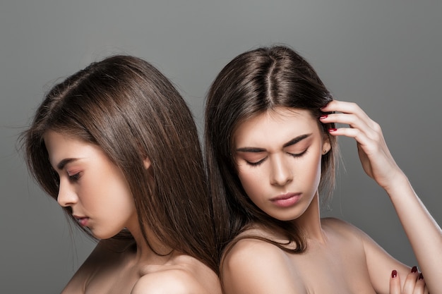 Ritratto di donne gemelle sconvolte con trucco naturale e capelli lunghi. moda