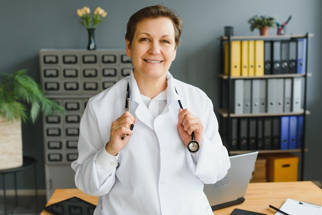 Ritratto di dottoressa di mezza età indossa un camice da medico bianco con uno stetoscopio intorno al collo