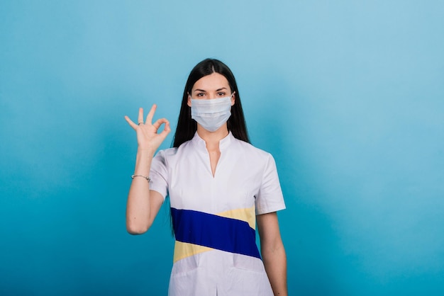 Ritratto di dottoressa in una maschera medica che distoglie lo sguardo isolato sul blu