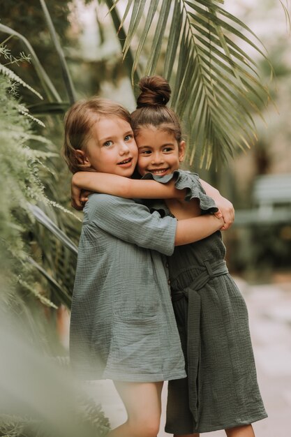 Ritratto di due affascinanti ragazze sorridenti appartenenti a diverse razze circondate da foglie tropicali