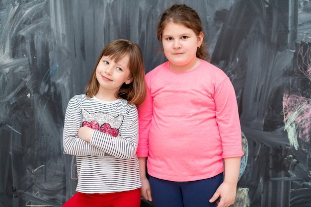 ritratto di due bambine carine felici in piedi davanti alla lavagna nera