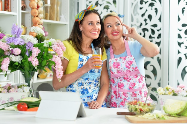 Ritratto di due belle giovani donne che cucinano insieme in cucina