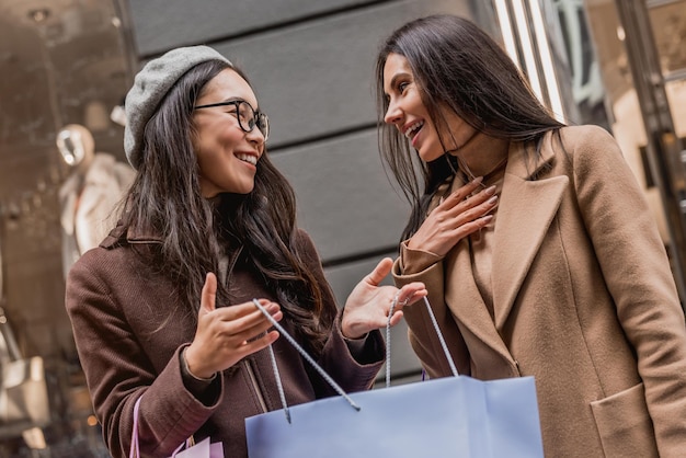 Ritratto di due belle giovani donne che si godono lo shopping in città