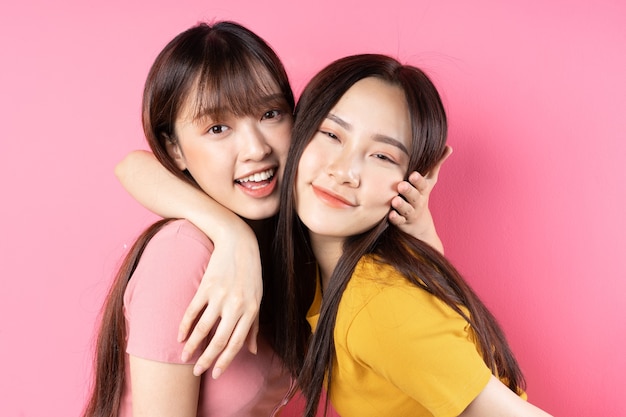 Ritratto di due belle ragazze asiatiche in posa sulla parete rosa