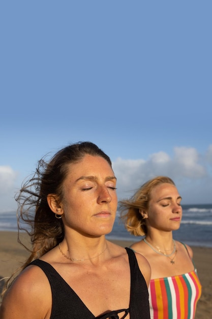 Ritratto di due donne che meditano con gli occhi chiusi sulla spiaggia